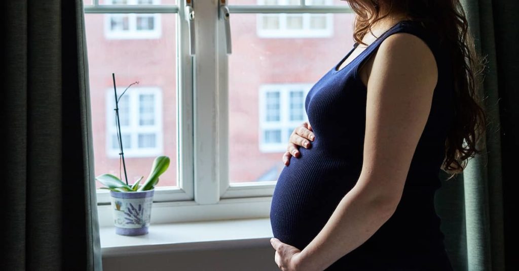 a pregnant woman looks out a window | Roberts Wilson, P.A.